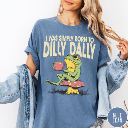 Comfort Colors tee in Blue Jean featuring illustrative style graphic of a frog sitting on a mushroom drinking tea
