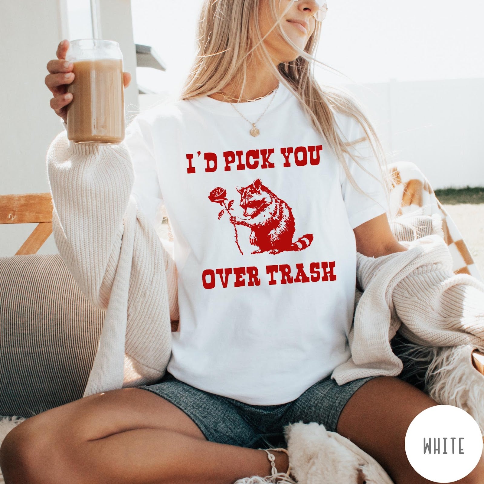 Comfort Colors tee in White featuring a whimsical graphic of a raccoon holding a red rose.