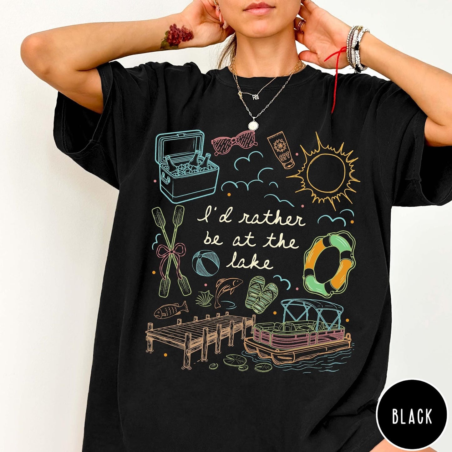 Comfort Colors tee in Black featuring lake vacation graphic with pontoon boat, dock, and summer accessories