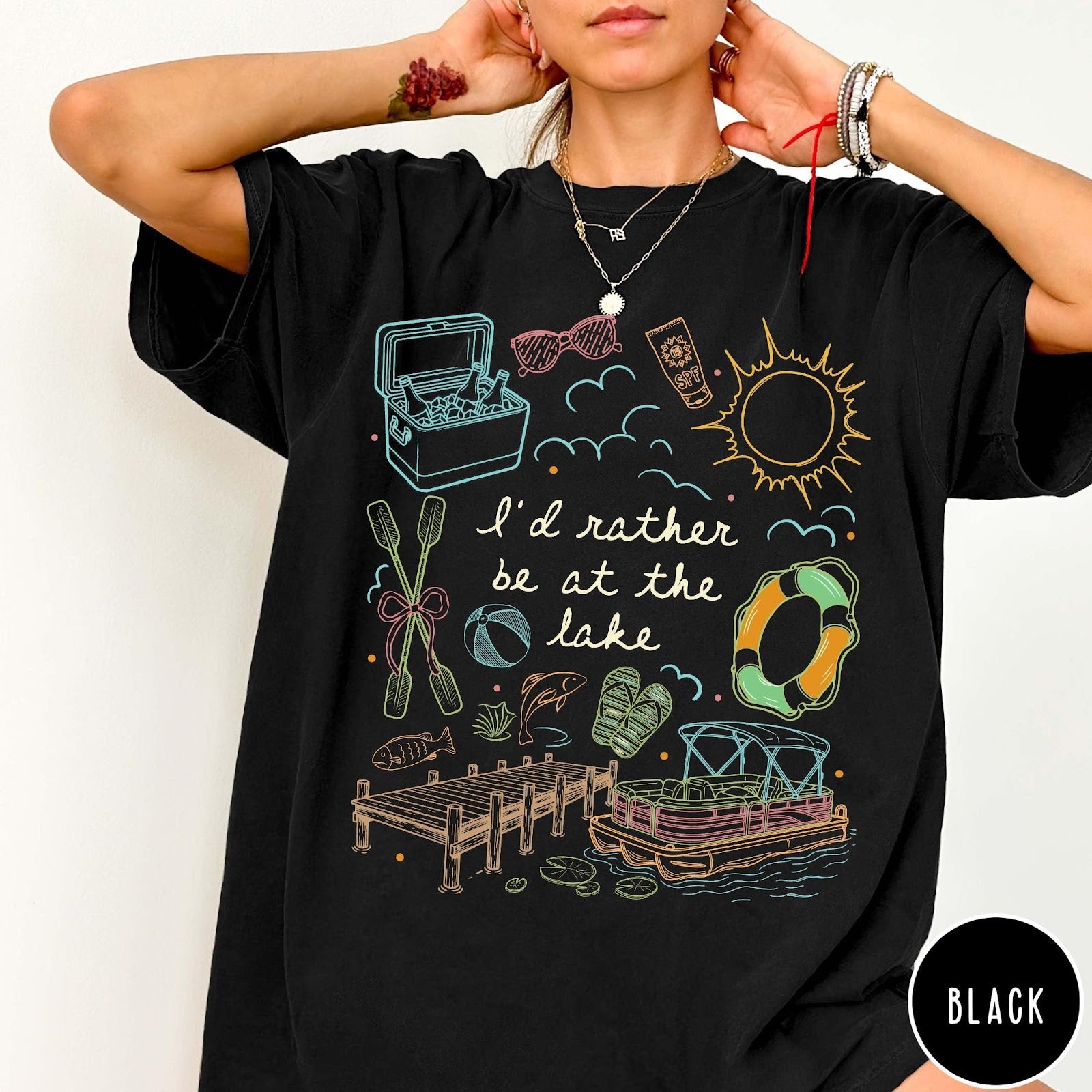Comfort Colors tee in Black featuring lake vacation graphic with pontoon boat, dock, and summer accessories