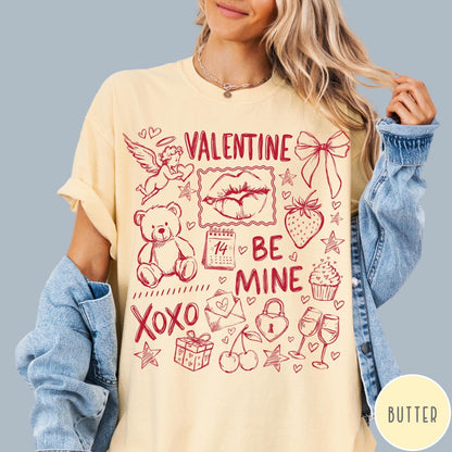Comfort Colors tee in Butter featuring Valentine's Day collage graphic with cupid, teddy bear, and romantic symbols