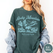 Comfort Colors tee in Blue Spruce featuring vintage style graphic of an elk standing in front of mountains