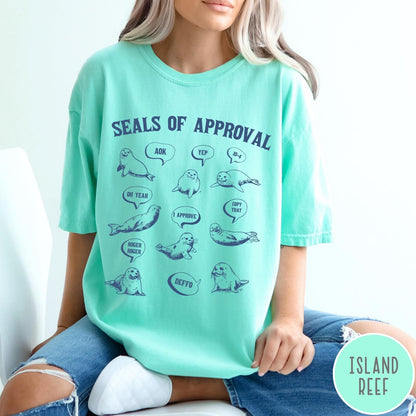 Comfort Colors tee in Island Reef featuring illustrative style graphic with multiple seals and speech bubbles saying approval phrases