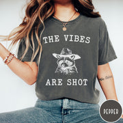 Comfort Colors tee in Pepper featuring graphic style raccoon wearing a cowboy hat and text The Vibes Are Shot