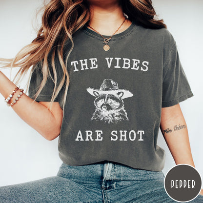 Comfort Colors tee in Pepper featuring graphic style raccoon wearing a cowboy hat and text The Vibes Are Shot