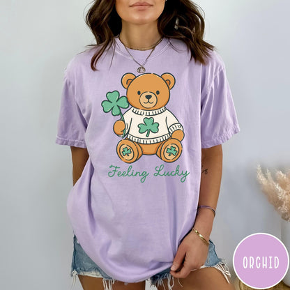 Comfort Colors tee in Orchid featuring illustrated teddy bear wearing a sweater and holding a four-leaf clover