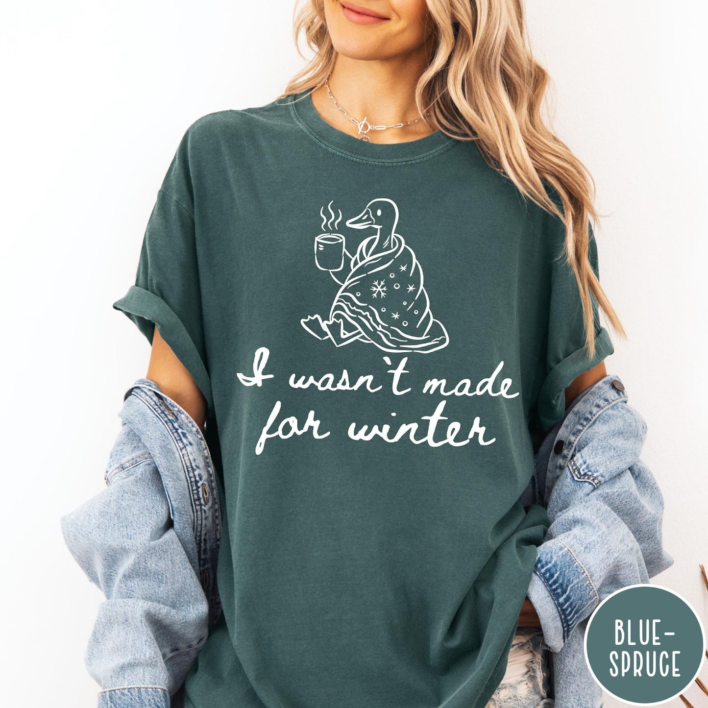 Comfort Colors tee in Blue Spruce featuring line art graphic of a duck wrapped in a blanket drinking coffee