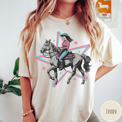 Comfort Colors tee in Ivory featuring retro cowgirl graphic with a woman riding a horse inside a star