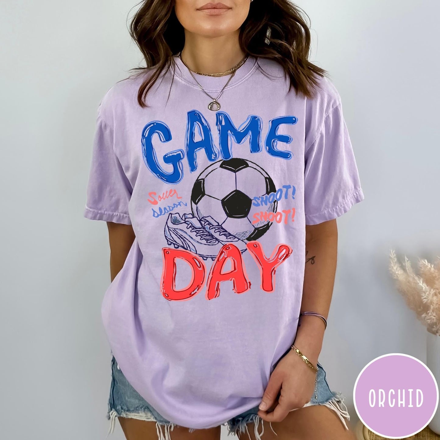 Comfort Colors tee in Orchid featuring soccer graphic with a ball, cleats, and Game Day text