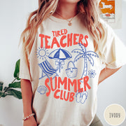 Comfort Colors tee in Ivory featuring summer vacation graphic with beach umbrella, palm tree, and beach chair.
