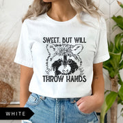 Comfort Colors tee in White featuring graphic style raccoon illustration with text Sweet, but will throw hands