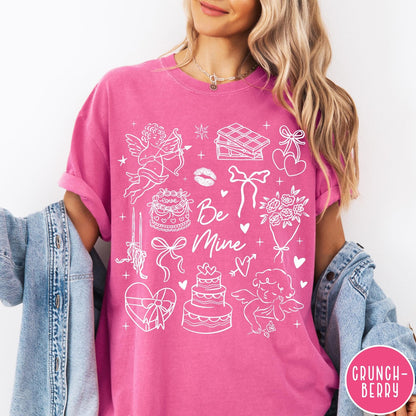 Comfort Colors tee in Crunchberry featuring Valentine's Day collage design with cupid, cake, flowers, and chocolate graphics