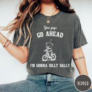 Comfort Colors tee in Pepper featuring illustration style graphic of a bear wearing a party hat riding bicycle