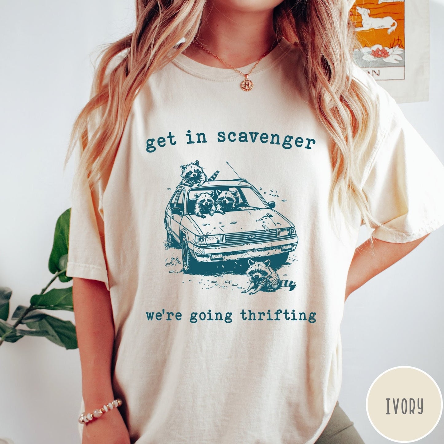 Comfort Colors tee in Ivory featuring illustrated style graphic of raccoons riding in a car and thrifting