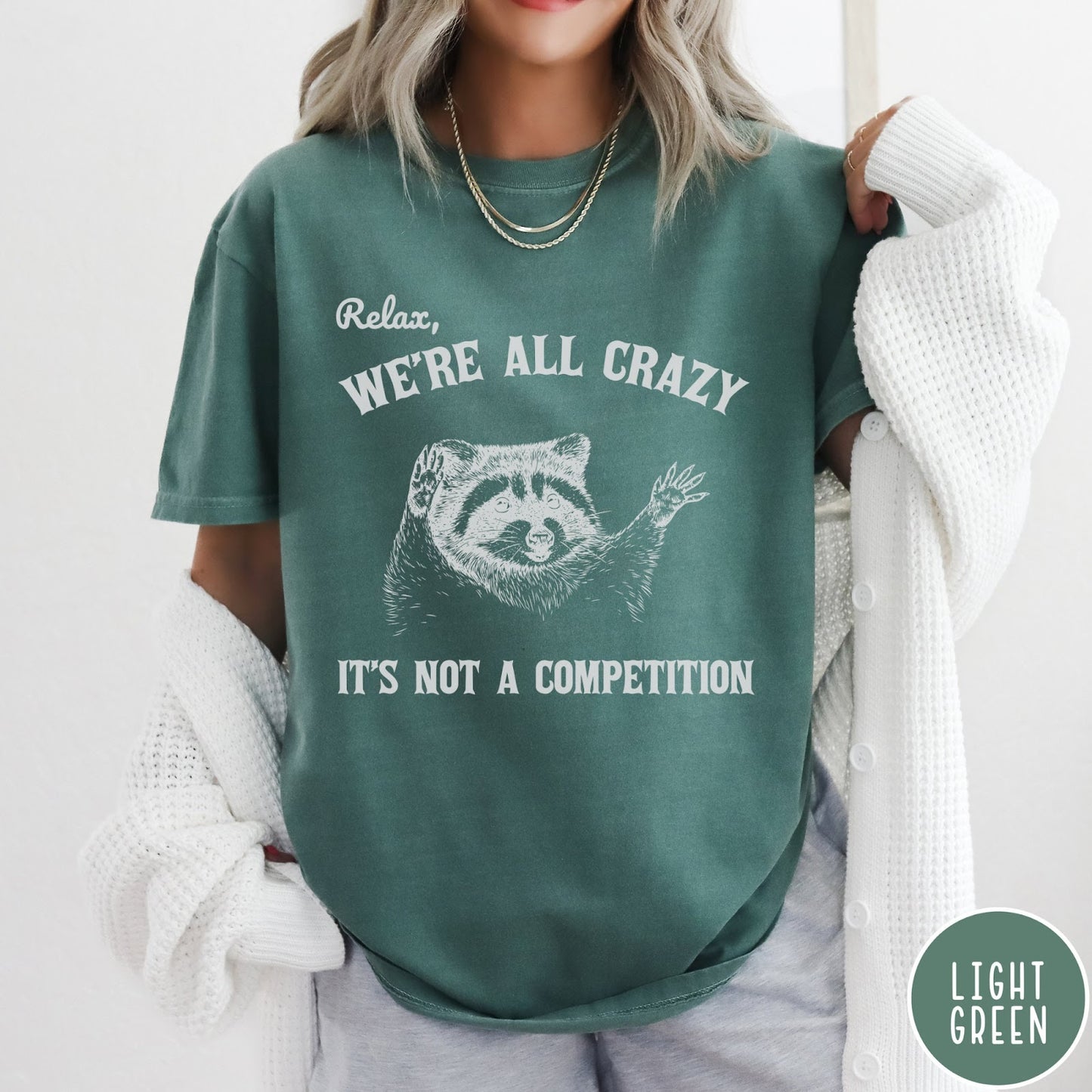 Comfort Colors tee in Light Green featuring screen print style graphic of a raccoon with text Relax We Are All Crazy