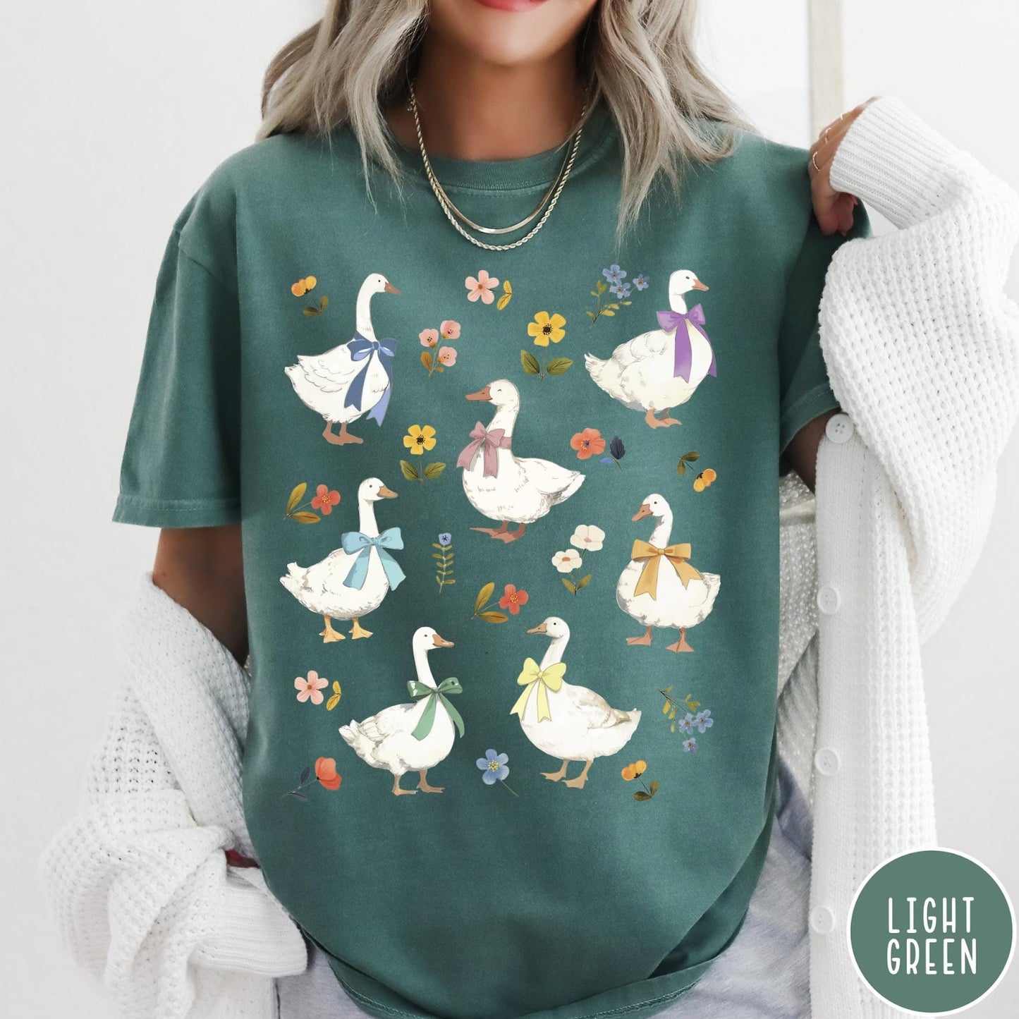 Comfort Colors tee in Light Green featuring vintage style graphic of several white geese wearing colorful bows and flowers