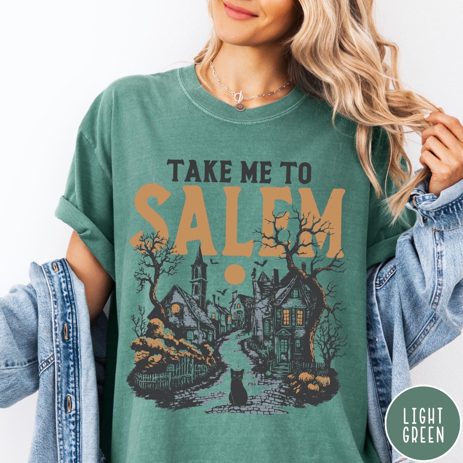 Comfort Colors tee in Light Green featuring vintage style Salem town scene with black cat and pumpkins