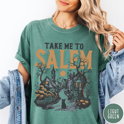 Comfort Colors tee in Light Green featuring vintage style Salem town scene with black cat and pumpkins