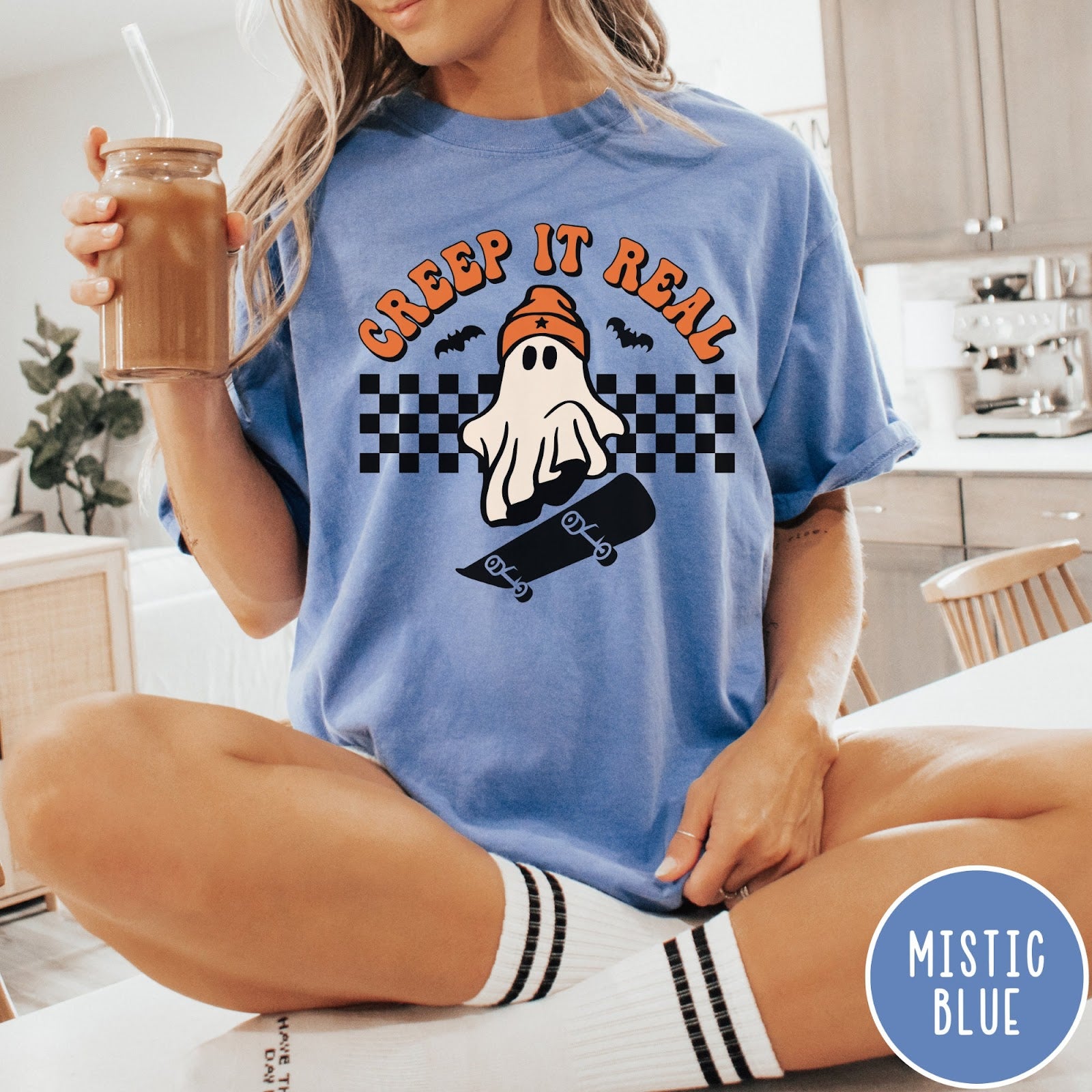 Comfort Colors tee in Mistic Blue featuring retro style ghost graphic with skateboard and checkered background pattern