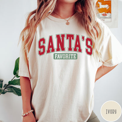 Comfort Colors tee in Ivory featuring collegiate style Santa's Favorite Christmas graphic with red and green text