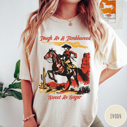 Comfort Colors tee in Ivory featuring western style graphic of a cowgirl riding a horse in desert