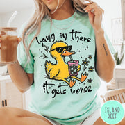 Comfort Colors tee in Island Reef featuring illustrated duck graphic wearing sunglasses and drinking a pink iced beverage