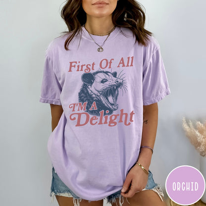 Comfort Colors tee in Orchid featuring illustrative opossum graphic with text First Of All I'm A Delight