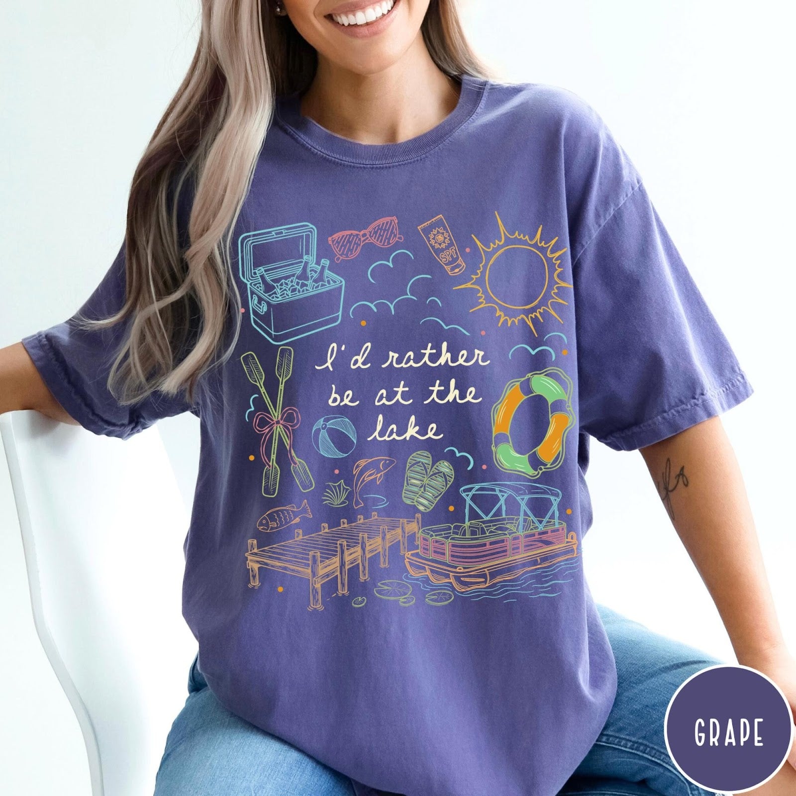 Comfort Colors tee in Grape featuring lake vacation graphic with pontoon boat, dock, and summer accessories