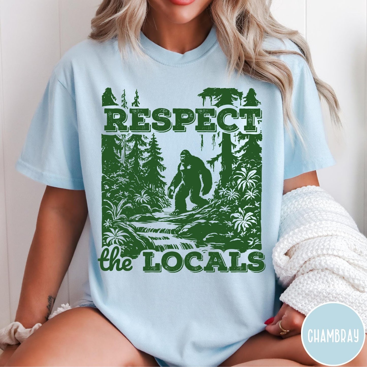 Comfort Colors tee in Chambray featuring vintage style graphic of Bigfoot walking through a forest by a river