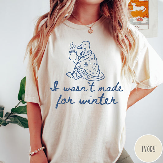 Comfort Colors tee in Ivory featuring line art graphic of a duck wrapped in a blanket drinking coffee