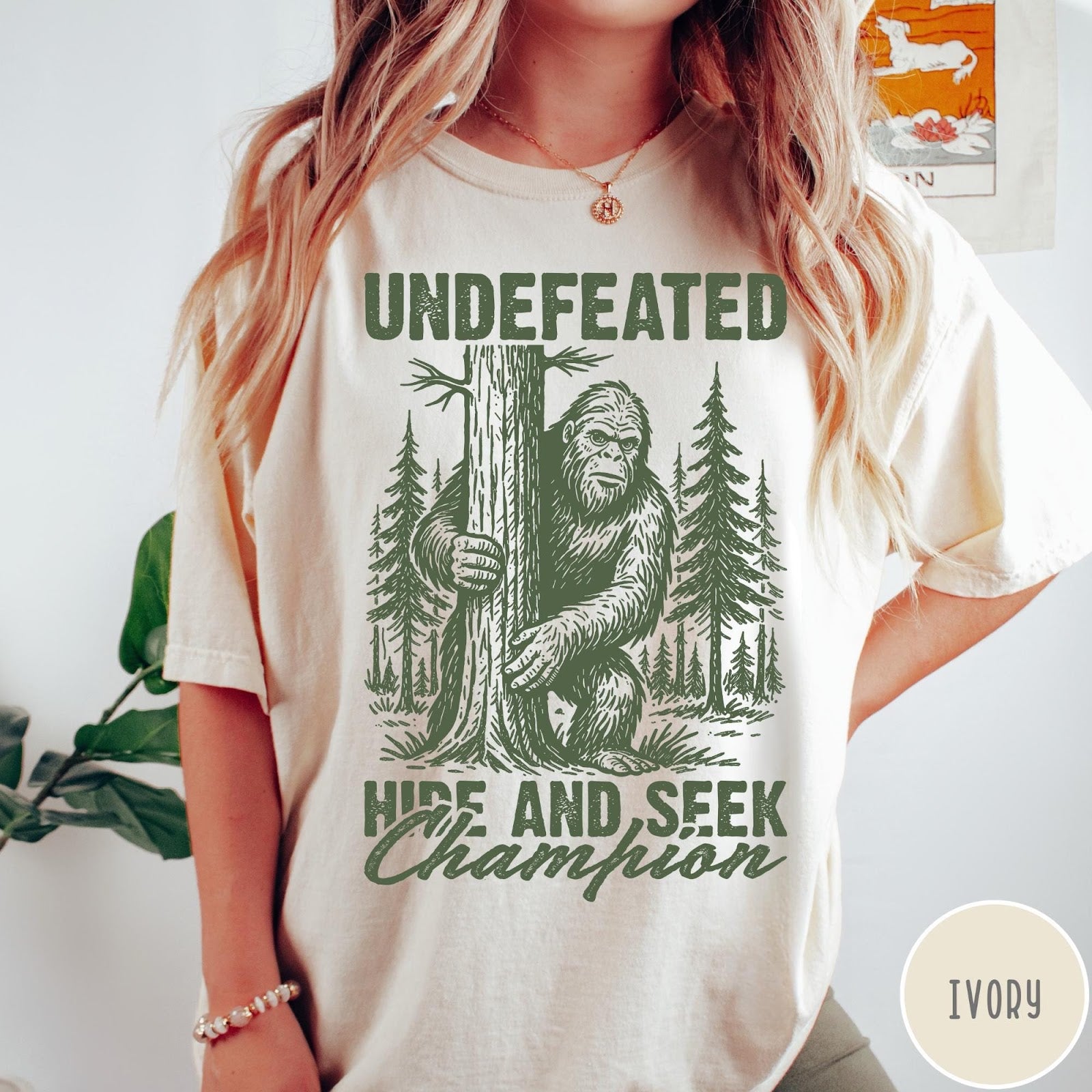 Comfort Colors tee in Ivory featuring vintage style Bigfoot graphic hiding behind a tree in the forest