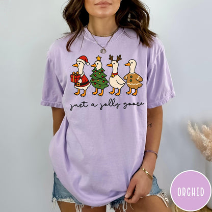 Comfort Colors tee in Orchid featuring festive geese dressed as Santa, Christmas tree, reindeer, and gingerbread