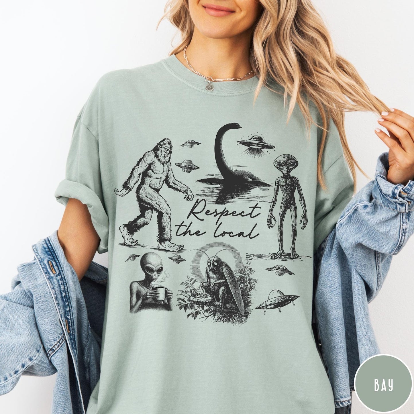 Comfort Colors tee in Bay featuring vintage style cryptid graphic with Bigfoot, UFOs, and alien creatures.
