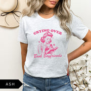 Comfort Colors tee in Ash featuring retro style graphic of a woman crying while reading a book