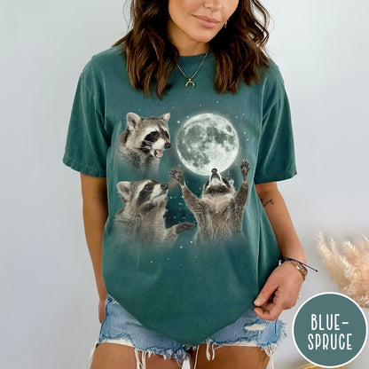 Comfort Colors tee in Blue Spruce featuring artistic graphic of three raccoons reaching toward a bright full moon