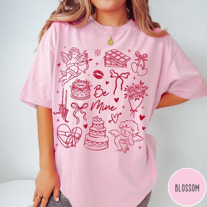 Comfort Colors tee in Blossom featuring Valentine's Day collage graphic with cupid, cakes, and romantic symbols.