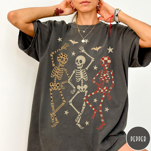 Comfort Colors tee in Pepper featuring dancing skeletons design with three skeletons, stars, and bats graphic