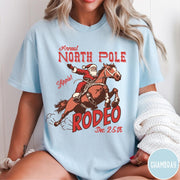 Comfort Colors tee in Chambray featuring vintage style graphic of Santa Claus riding a bucking rodeo horse
