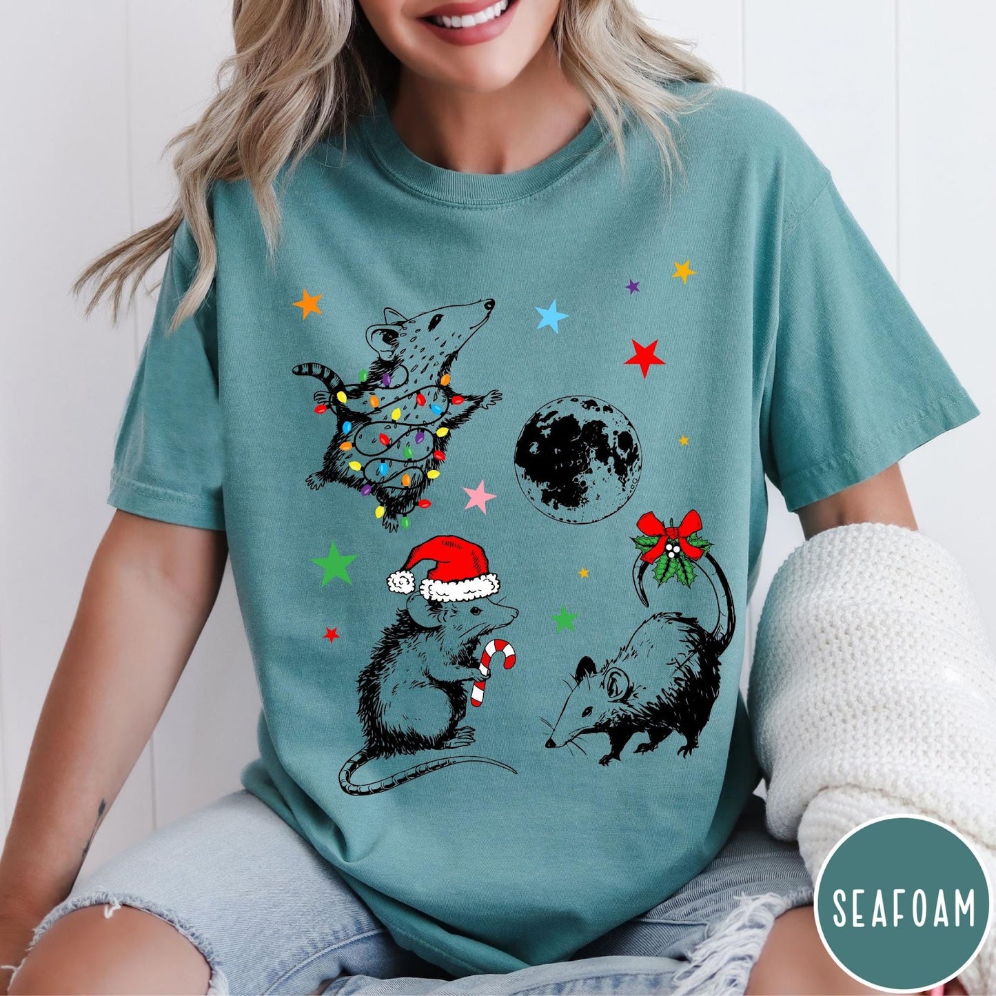 Comfort Colors tee in Seafoam featuring holiday possum graphic with Christmas lights, candy cane, and moon.