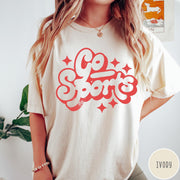 Comfort Colors tee in Ivory featuring retro sports style graphic with Go Sports text and star accents