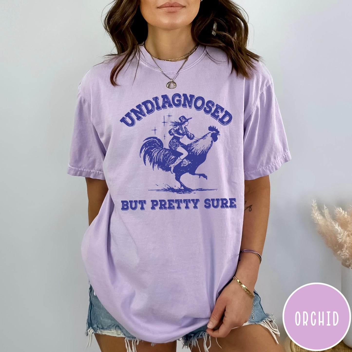 Comfort Colors tee in Orchid featuring western style graphic of a cowgirl riding a large rooster