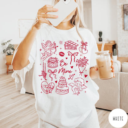 Comfort Colors tee in White featuring Valentine's Day collage graphic with cupid, cakes, and romantic symbols.