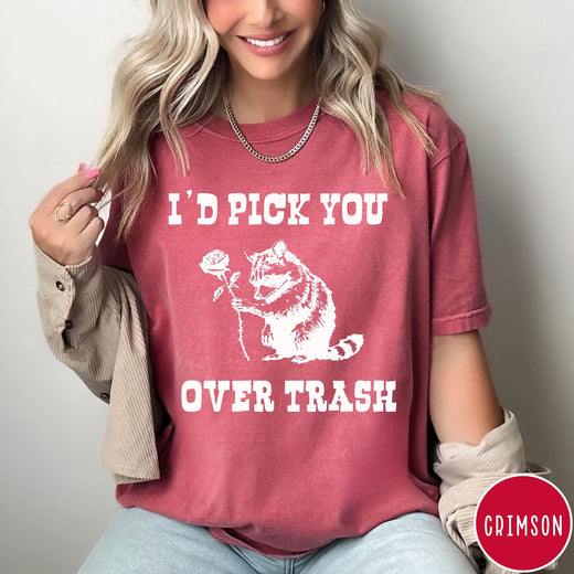 Comfort Colors tee in Crimson featuring a whimsical graphic of a raccoon holding a white rose.