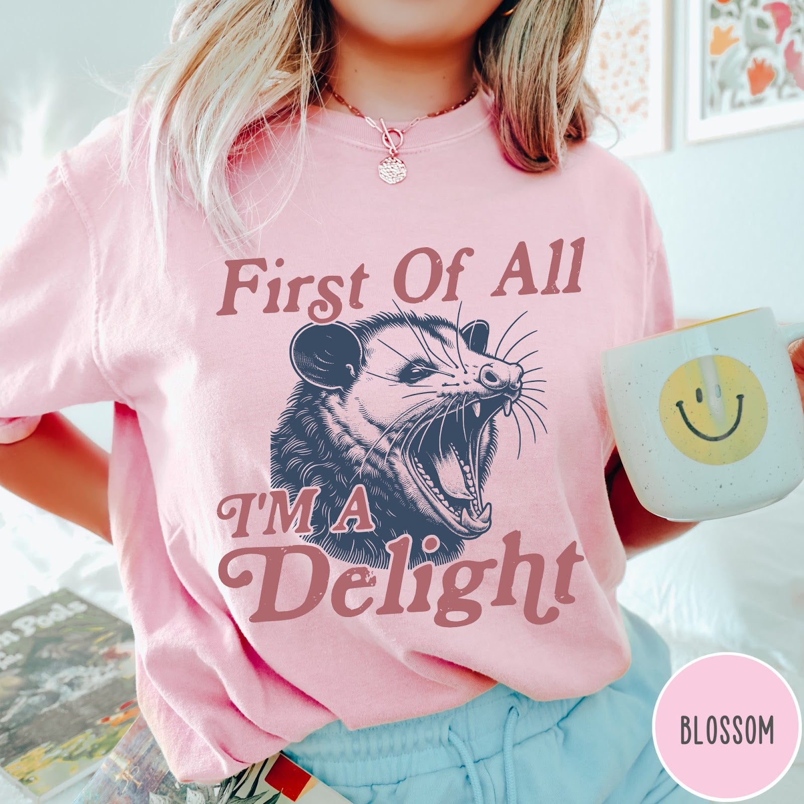 Comfort Colors tee in Blossom featuring illustrative opossum graphic with text First Of All I'm A Delight