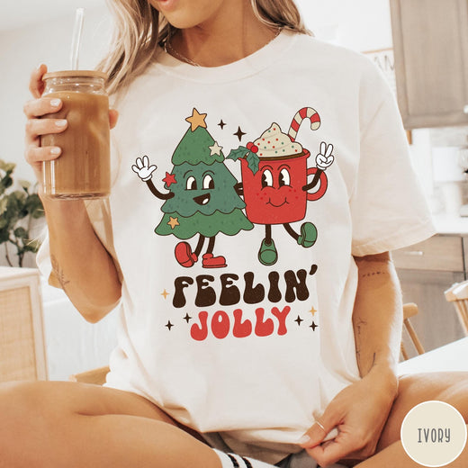 Comfort Colors tee in Ivory featuring retro style graphic of a cartoon Christmas tree and cocoa mug