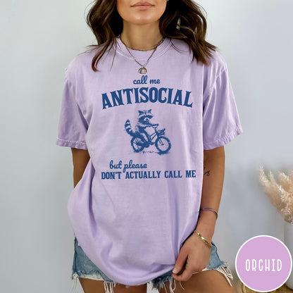Comfort Colors tee in Orchid featuring graphic style illustration of a raccoon riding a bicycle