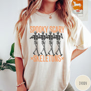 Comfort Colors tee in Ivory featuring dancing skeletons graphic with Spooky Scary Skeletons text in orange
