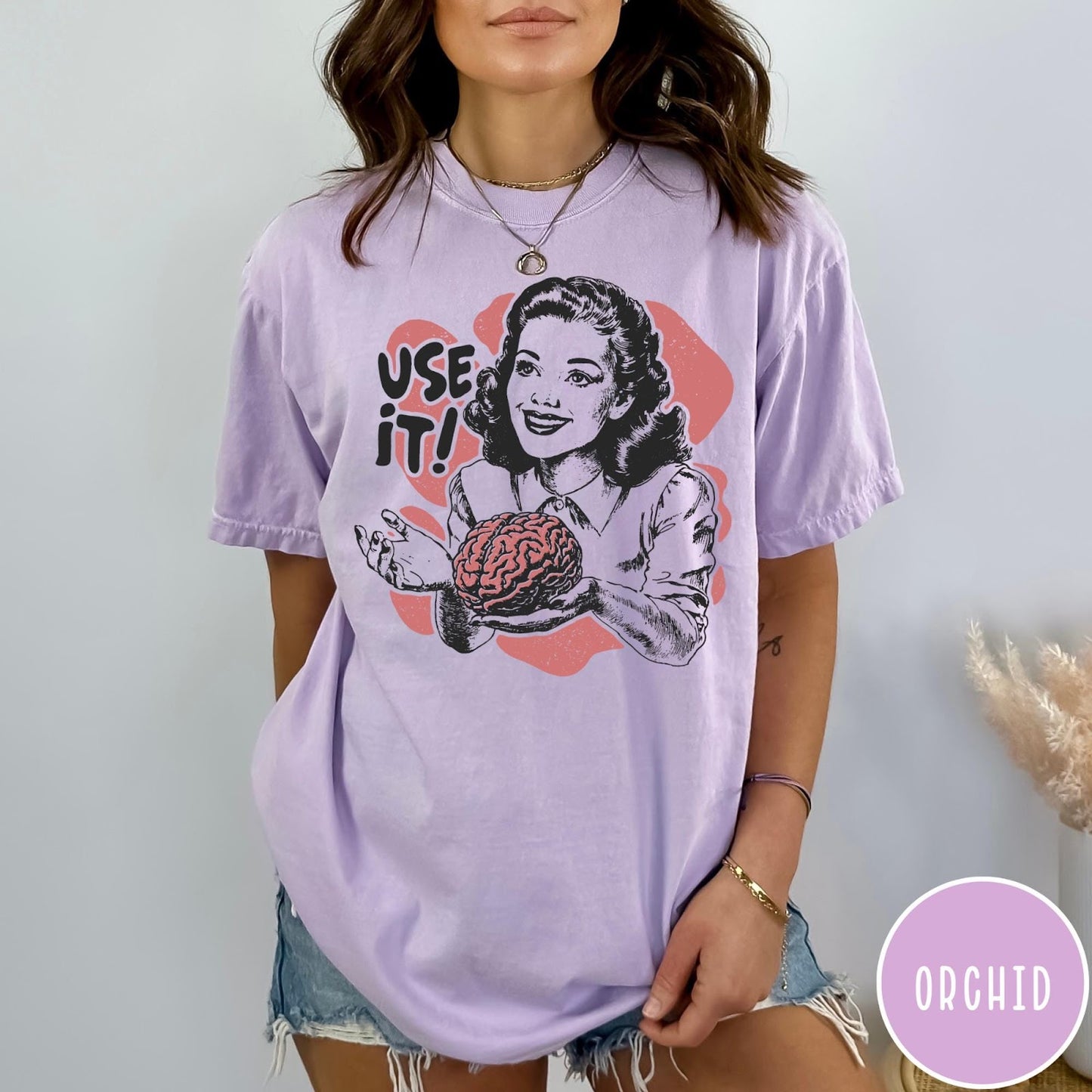 Comfort Colors tee in Orchid featuring retro style graphic of a woman holding a human brain