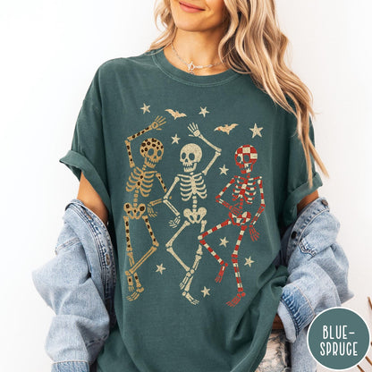 Comfort Colors tee in Blue Spruce featuring dancing skeletons design with three skeletons, stars, and bats graphic
