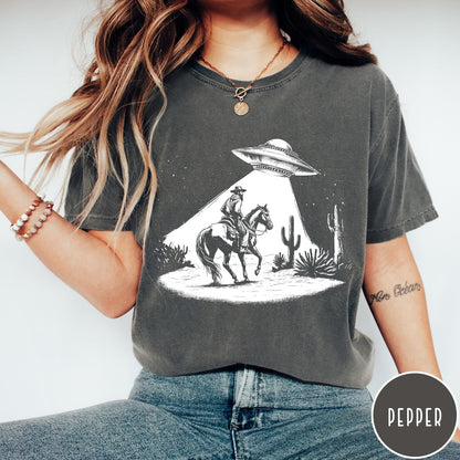 Comfort Colors tee in Pepper featuring western graphic style cowboy on horseback being abducted by a UFO